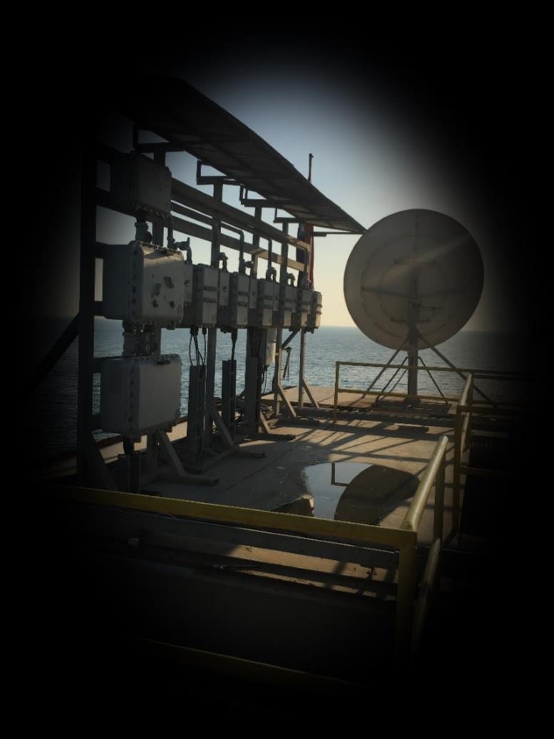 A satellite earth station antenna on a steel platform at dusk